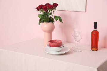 Wall Mural - Vase with roses, dishes and wine on tablecloth near pink wall in room