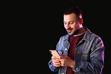 Wall Mural - young man using mobile phone on dark background