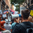 © David - Person holding megaphone during protest, focused perspective, urban street, engaged crowd