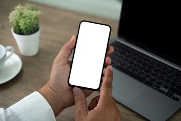 Wall Mural - A person is holding a cell phone and laptop on a desk.