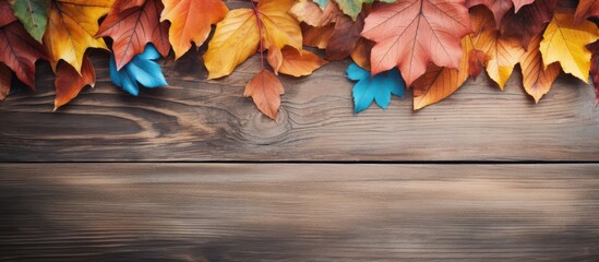 Poster - Rustic wooden background featuring vibrant autumn leaves in orange, yellow, and blue at the top with ample copy space below for text.
