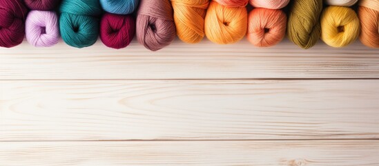 Poster - Colorful yarn skeins arranged in a row on a light wooden surface with warm tones of orange, pink, and green creating a cozy vibe.
