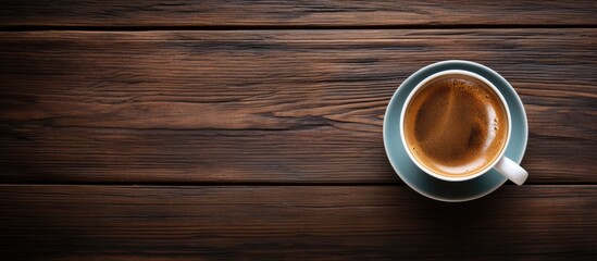 Poster - Aerial view of a gray cup of espresso on dark wooden surface with rich coffee color filling the cup surrounded by ample negative space for text