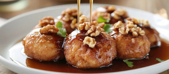 Poster - Golden brown round fritters drizzled with dark syrup and topped with walnuts on a white plate creating a tempting dessert scene.