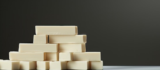 Poster - White chocolate bars stacked on a gray background with soft shadows highlighting their creamy texture and angular edges in a minimalist composition