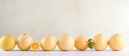 Poster - Fresh pomelo fruits in a row on a light marble background, with one half revealing juicy pulp, showcasing pale yellow and green tones.