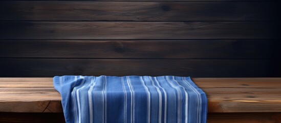 Poster - Wooden table surface with a blue striped towel draped on the left, dark wood background, ample negative space for text or image placement.