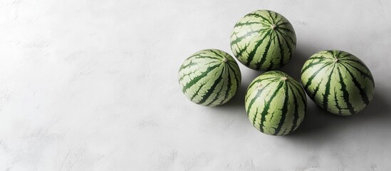 Poster - Fresh watermelons with green striped skins arranged in a cluster on a light grey background highlighting their textures and vibrant colors.