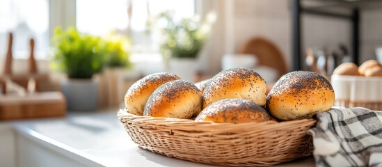 Poster - Golden-brown sweet buns with poppy seeds in a woven basket on a sunny kitchen counter with greenery in the background for a cozy breakfast setting