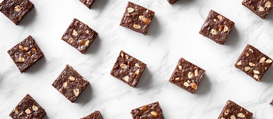 Aufkleber - Richly textured brownies with nuts arranged in a grid pattern on a white marble background showcasing their enticing presentation and cocoa flavor.
