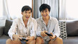 © aFotostock - Happy gay couple enjoy playing game together sitting sofa at home living room lifestyle. Friendship gamer men use joystick playing have fun happy time. Two best friends LGBTQ relation partner home