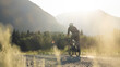 © Cavan Images - Gravel biker on a dirt path during golden hour in a calm valley.