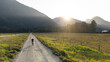© Cavan Images - Gravel cyclist rides a rural road in sunlight near distant mountains