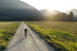 © Cavan Images - Gravel biker on a dirt road during golden hour in a serene valley