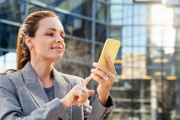 Wall Mural - Businesswoman using her smartphone outdoors in city