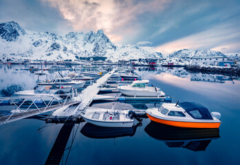 Wall Mural - small fishing boats against the background of a giant snow-capped peak. dramatic winter cityscape of