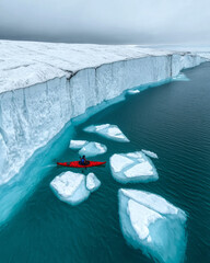 Aufkleber - A kayaker navigating through icebergs that have broken off from a glacier,