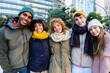 © Xavier Lorenzo - Happy diverse young friends in winter clothes smiling at camera standing together outside. Portrait of multiracial student people hugging each other at college campus