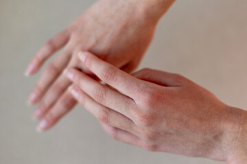 Close-up of Dry Hands with Minimal Background. Close-up image of two hands with dry skin, emphasizing texture and natural details, against a neutral blurred background.