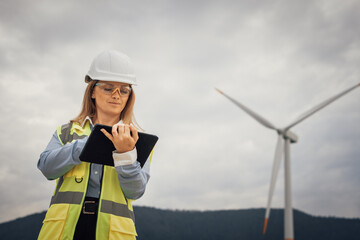 Poster - A skilled female engineer is actively working at a wind farm, utilizing her tablet to effectively manage various aspects of the project, ensuring smooth operations and progress tracking
