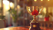© Angga - Golden trophy on wooden table with sunlight creating a victory atmosphere