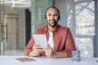 © Liubomir - A man with a headset and a tablet computer in his hands looks into the camera, a support service worker at work, advising clients. Web camera view.