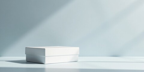 Poster - A simple white box rests on a pale blue surface, bathed in soft, natural light