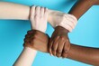 © New Africa - Stop racism. People of different skin colors joining hands on light blue background, closeup