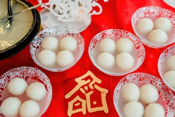 Wall Mural - Tang Yuan Dessert Table A homely table setup with bowls of sweet glutinous rice balls in a clear broth, accompanied by decorative paper cuttings of the Chinese character