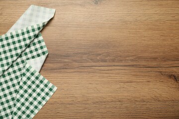 Wall Mural - Green checkered tablecloth on wooden background, top view. Space for text