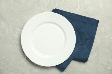 Wall Mural - Blue napkin and empty plate on grey marble table, top view