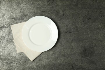 Wall Mural - Light napkin and empty plate on grey table, top view. Space for text