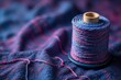 © Anulak - Indigo-dyed yarn spool in a woven fabric background, dyed thread, handmade craft