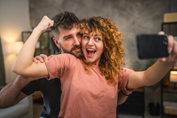 woman show muscles in the sports wear and take a self portrait with man