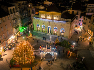 Wall Mural - Aerial view of Corfu Town, Greece, adorned with Christmas lights and decorations. The Liston, a historic arcade, is prominent, showcasing the festive atmosphere.