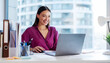 © Home-stock - Smiling European female manager dressed in shirt sitting at her workplace in office, working on laptop computer, panorama, free space