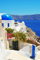 Wall Mural - Oia village on Santorini island, Greece. Traditional and famous church with blue dome and white houses over the Caldera, Cyclades islands Aegean sea.
