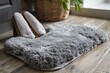 © nsit0108 - Gray fluffy bathroom rug with matching slippers resting on wooden floor, creating a cozy and comfortable atmosphere