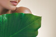 © Buyanskyy Production - Close-up of a woman's lips and bare shoulder with a dewy green tropical leaf, symbolizing natural beauty and skincare. Ideal for eco-friendly, wellness, and organic beauty concepts.