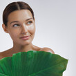 © Buyanskyy Production - Portrait of a young Caucasian woman with glowing skin holding a large green tropical leaf, symbolizing natural beauty and eco-friendly skincare. Perfect for wellness and spa concepts.