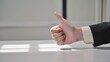 © ittipol - Thumbs Up Approval: A close-up shot of a businessman's hand giving a thumbs up gesture, signifying approval, positivity, and success. The image evokes a sense of confidence and encouragement.