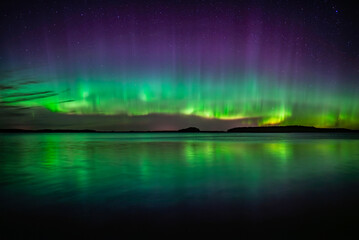 Wall Mural - northern lights dancing over calm lake in north of sweden