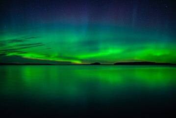 Wall Mural - northern lights dancing over calm lake in north of sweden