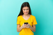 © luismolinero - Young caucasian woman isolated on blue background sending a message with the mobile