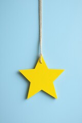 Poster - a vibrant yellow star hanging against a soft blue background, perfect for design projects and creati
