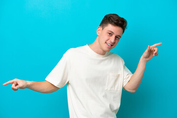 Wall Mural - Young handsome Brazilian man isolated on blue background pointing finger to the laterals and happy