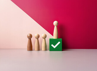 Poster - Grainy image of wooden figures; one stands taller on a green block with a checkmark, suggesting achievement and standing out from the crowd.  The background has a pink and maroon color split.  Texture