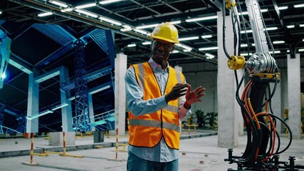 Leinwandbilder - Construction worker demonstrates robotic technology in industrial facility during day