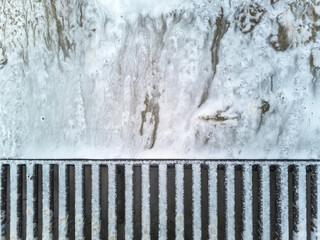 Soap sud waste flows to floor drain grid in car washing garage, close-up.