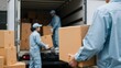 © PhotoMaster - Team of movers carefully carrying boxes from a truck, focused on organization and safety, providing reliable packing and moving services for residential or commercial needs